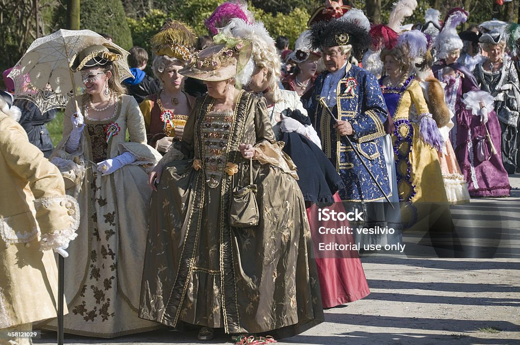 Carnival parade "Stra (Venice), Italy - March 20, 2011: Carnival costume parade along a path of the ornamental garden of Villa Pisani, during the celebration of the event named Carnevale in Villa (Carnival in Villa). Each year this event takes place in the beautiful garden of Villa Pisani of Stra (Venice). Participating in the parade are some of the best masked teams from the previous masked celebrations held in Venice, a few weeks earlier, during the famous Venice Carnival. Begun in the early 18th century, Villa Pisani, now national museum, is a majestic patrician villa, one of the most famous examples of Venetian villa facing Brenta river along Riviera del Brenta." Abundance Stock Photo
