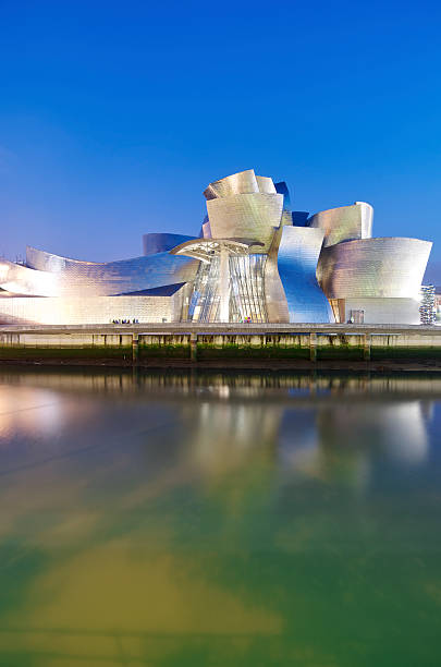 Guggenheim "Bilbao, Spain - July 30, 2011: night view of the  Guggenheim Museum and Nervion river at sunset. Guggenheim Museum is dedicated  exhibition of modern art and was  designed by architect Frank Gehry." frank gehry building stock pictures, royalty-free photos & images
