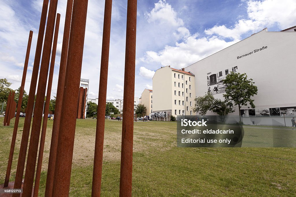 Tourists at the Berlin Wall Memorial Bernauer Strasse "Berlin, Germany - June 10th, 2012: Wide angle view of part of the Berlin wall memorial at Bernauer Strasse,with tourists scattered around observing the various educational and symbolic elements of the memorial. The orange metal columns on front mark the exact location where the west wall once stood; metal markings on the floor symbol structures that were removed in order to create a neutralized zone between the two walls seperating berlin, as well as escape tunnels routes." Architectural Column Stock Photo