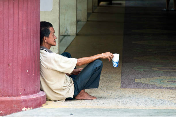 Penang, Malaysia - August 5, 2011: Chinese Malaysian Man Begging outside the Wat Chayamangkalaram Thai Temple in Penang, Malaysia.