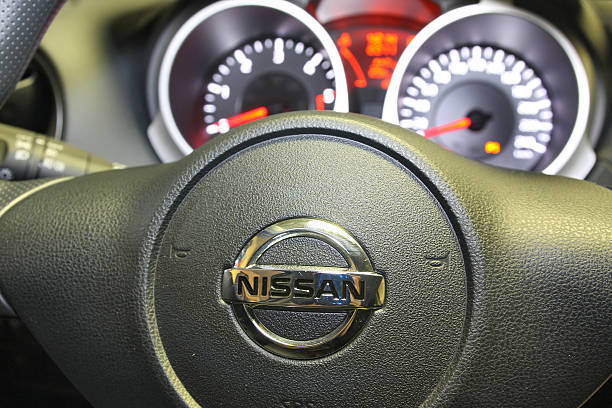 Ambronay, France - August 19, 2012: Nissan logo on the steering wheel of a car with the counters in the background