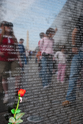 Washington DC, USA - April 9, 2008: Reflected in the stone slabs of the Vietnam Veterans Memorial are visitors looking at some of the 58,000-plus names of American military personnel killed during the war in Vietnam. The reflection of the Washington Monument is also visible