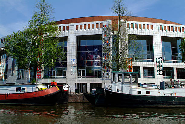 Netherlands, Amsterdam "Amsterdam, Netherlands - June 13th 2006: boats on Amstel canal and Stopera - the Amsterdam Opera House - behind" stopera stock pictures, royalty-free photos & images