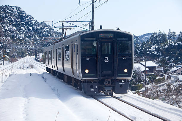 Japanese train pulling into station on snowy day stock photo