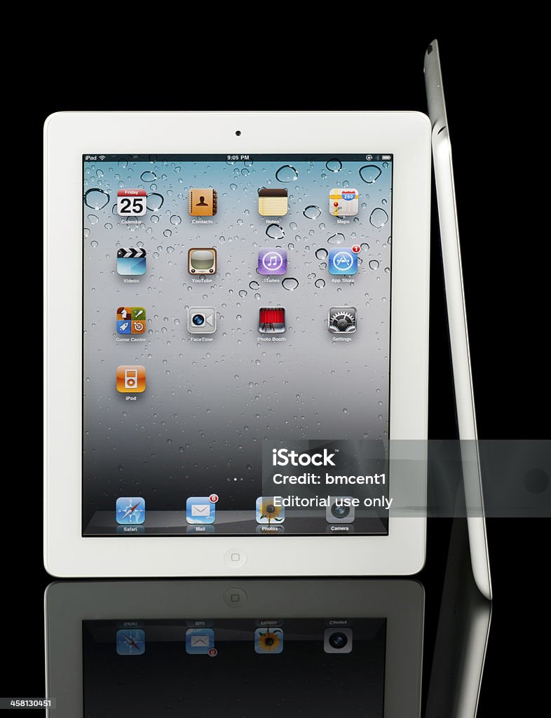 Two Apple iPad 2 tablets, isolated on reflective black surface "Frederick, MD, USA - March 25, 2011: A white Apple iPad 2 tablet faces directly toward the viewer, a second iPad 2 leans up against the first to show the product's slim form factor when viewer on edge." At The Edge Of Stock Photo