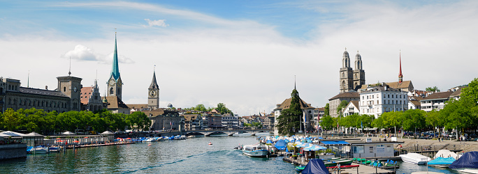 Zurich, Switzerland - June 5, 2011: View of the old town part of the city of Zurich along the River Limmat.  On the left can be seen the clock towers of Fraumunster abbey and St. Peters church. On the right can be seen the two towers of the Romanesque style church Grossmünster  (\