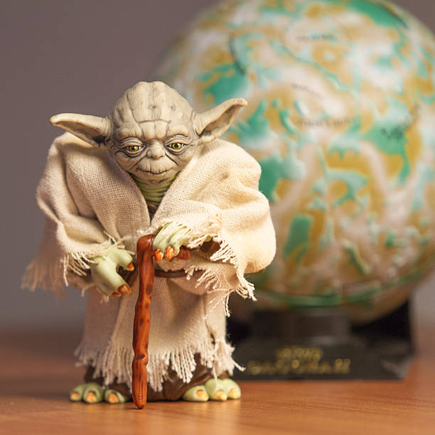 Yoda Master "York, USA - December 21, 2011: The character Yoda, from the Star Wars film franchise with a cane. A planet is in the backgroud. Shallow DOF." star wars stock pictures, royalty-free photos & images