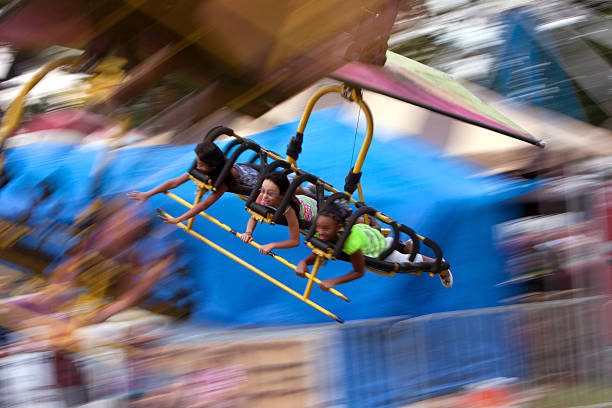 Motion Blur Of Teenagers On A Flying Carnival Ride "Lawrenceville, GA, USA - September 15, 2012:  Unidentified teenagers enjoy a flying carnival ride on the midway at the Gwinnett County Fair." midway fair stock pictures, royalty-free photos & images