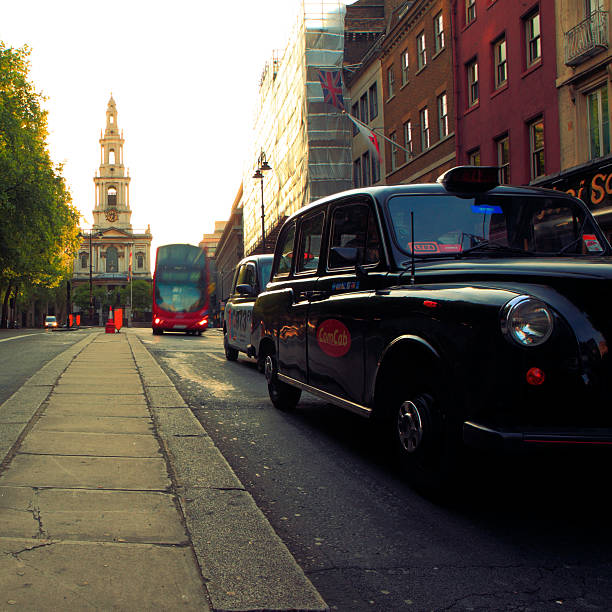 London, United Kingdom - May 3, 2011: London at 6:44 AM on a Tuesday morning a traditional London black cab or hackney-carriage travels Westward on the Strand. The camera is looking East toward St. Mary le Strand church in the distance. St. Mary le Strand is a Church of England church at the eastern end of the Strand in the City of Westminster, London. It lies within the Deanery of Westminster (St Margaret) within the Diocese of London.  This image had had minor global cross-processing applied in post production. Taken during IStockalypse London.