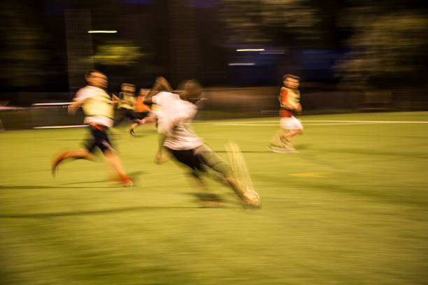 American Football Clash Unfolds as Professional Male Athletes Tackle Competition on a Green Outdoors Field. Agile Blue Footballers Running Away From Competition