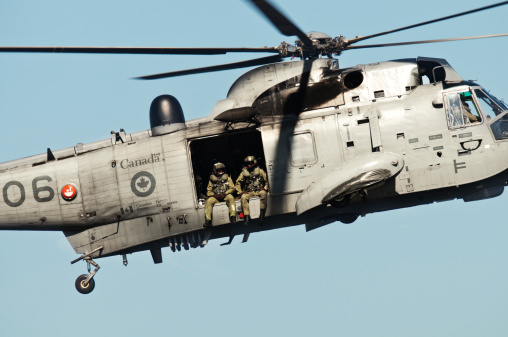 Halifax, Nova Scotia, Canada - August 16, 2011: A Canadian Military Sea King helicopter with crew in the cargo bay door doing a low flyby along the Halifax Waterfront.