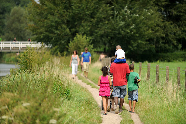 Happy family with dog walking in the field back to camera
