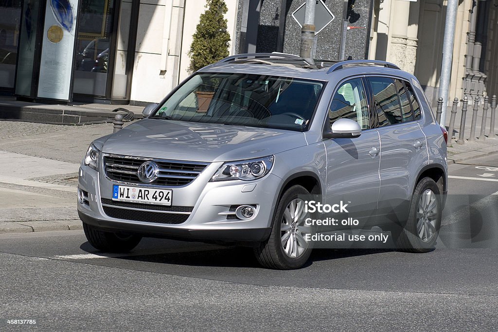 VW Tiguan (Type 5N) "Wiesbaden, Germany - April 7, 2011: A man in a grey-metallic Volkswagen (VW) Tiguan turning right on a street corner in Wiesbaden on a sunny spring morning. Volkswagen (VW) Tiguan is a compact crossover vehicle (also known as CUV) based on the platform of the Volkswagen Golf and was launched in 2007. VW is a brand of the Volkswagen Group, which is a German automobile manufacturing group based in Wolfsburg, Germany and founded in 1937. Some motion blur." Adult Stock Photo
