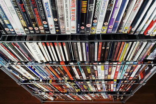 Durham, England - August 27, 2011: Several CDs and DVDs in their cases are inserted in a DVD rack on the floor. The DVDs and the CDs come mostly from the British and Italian market.