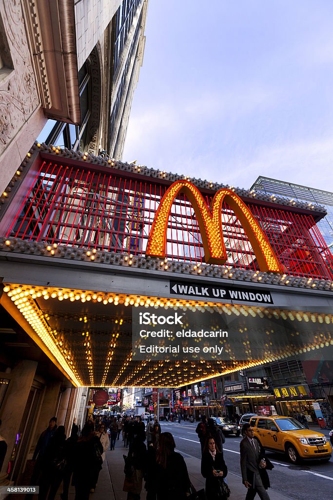 McDonald's at 42nd Street New-York "New-York, USA - November 6th, 2012: Wide angle view of big M sign at the entrance of the McDonald's branch located at 220 W 42nd St. (between 7th and 8th avenues) in Manhattan, with sky scrapers surrounding it, and many pedestrians walking on the sidewalk beneath it." 42nd Street Stock Photo