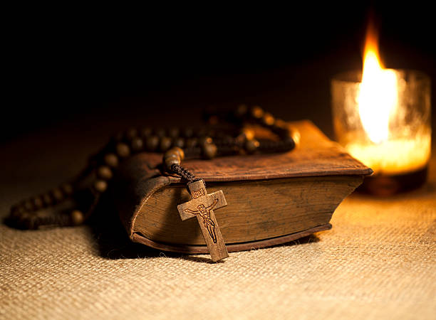 istock Old Bible and Rosary beads by lit candle 458146551