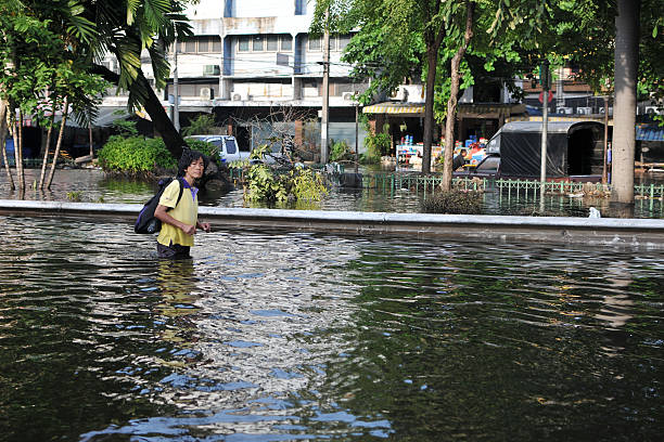 Bangkok, Thailand - November 4, 2011: A woman wades through a flooded street in Pinklao district.