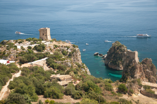 Scopello, Italy - August 2, 2012: The Tonnara of Scopello. On the background, the faraglioni and the observation tower. Scopello is near Castellammare Del Golfo, Trapani, Sicily, and is a beautiful sea location visited by thousand of tourists every year, also for the near Zingaro Reserve.