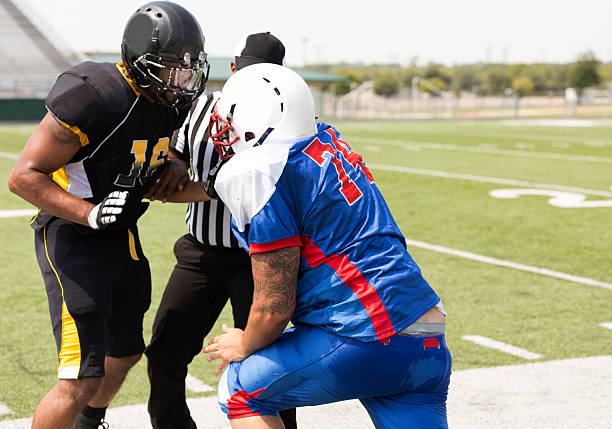 istock Sports:  Football players separated by referee during game. 458227395