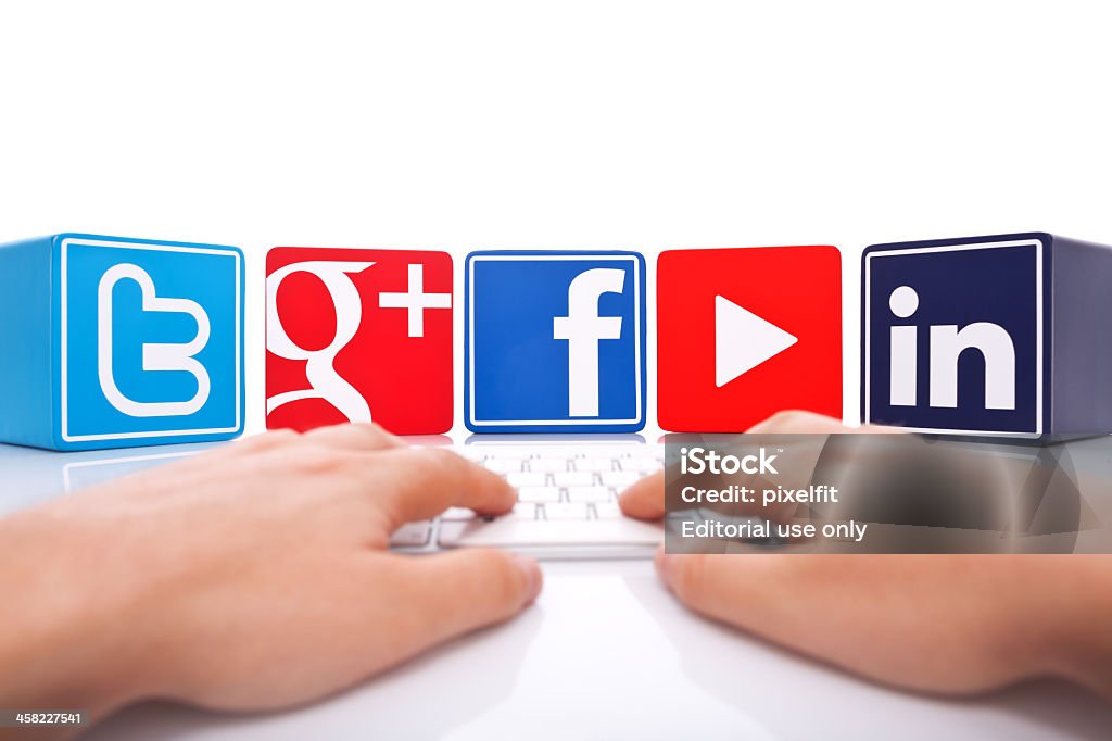 Social Network Sofia, Bulgaria - July 31, 2013: Studio shot of color plastic cubes with facebook, google+, twitter, linkedin and you tube signs. In front man's hands typing on computer keyboard. Isolated on white background. Adult Stock Photo
