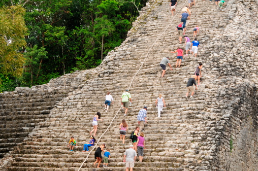 A!oba, Mexico - November 20, 2012: Fortunate visitors having the opportunity to climb Coba's Mayan pyramid 'Nohoch Mul' because many in Mexico are now prohibiting the chance due to accidents. The city was occupied between 100-1000AD.