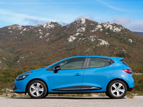 Rijeka, Croatia - October 11th, 2012: New Renault Clio parked on Grobnik flats with the mountains in the background. Fourth generation of popular Renault city hatchback is introducing new design language that all future Renault models will follow. It's somewhat bigger then a predecessor, but around 100 kilograms lighter.