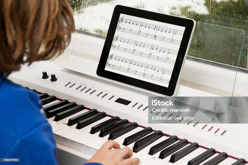 Enfant jouant du piano avec iPad en feuille de musique - Photo de Piano libre de droits