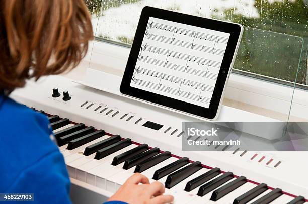 Photo libre de droit de Enfant Jouant Du Piano Avec Ipad En Feuille De Musique banque d'images et plus d'images libres de droit de Piano