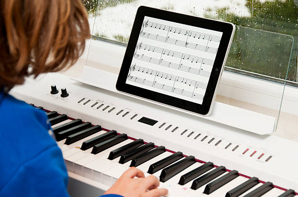 child playing the piano with iPad as sheet of music stock photo