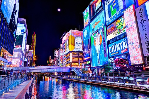 Osaka, Japan - November 25, 2012: Tourists stroll under the famed advertisements of Dotonbori Canal. With a history reaching back to 1612, the district is now one of Osaka's primary tourist destinations.