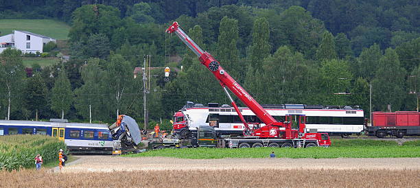 Swiss train crash in Granges-pres-Marnand Granges-pres-Marnand, Switzerland - July 30, 2013 :  The crash happened in Granges-pres-Marnand in Vaud canton in the early evening of  july 29, 2013 .The driver of one of the trains died and 35 people were injured.This photo was taken the morning after.Investigators are at the scene to try to determine the cause of the crash, and workers  prepare the attachment of the crane on the train. They have to remove the damaged train out of the track to restore circulation derail stock pictures, royalty-free photos & images