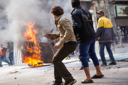 Cairo, Egypt - November 21, 2011: Protesters on Mohamed Mahmoud Street in clashes with police. The Protesters are throwing rocks at the police to stop them from entering Tahrir square and the peaceful demonstration.