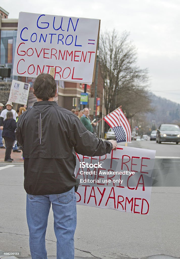 Протестующий показывает пистолет контроля указателям на прохожих, в Эшвилле - Стоковые фото Американская культура роялти-фри