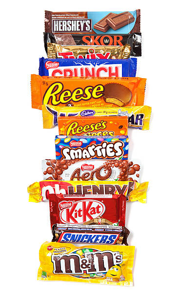 Row of Assorted Chocolate Products Toronto, Canada - May 10, 2012: This is a studio shot of a variety of chocolate products made by various companies including Nestle, Hershey's, Mars Inc., and Cadbury isolated on a white background. cadbury plc photos stock pictures, royalty-free photos & images