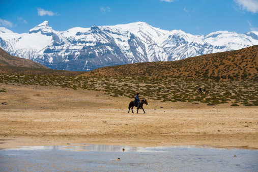 Dhankar, India - June 7, 2009: An unidentified Buddhist pilgrim rides a horse on pilgrimage to a holy lake among the Himalayan mountains in the Spiti Valley on June 7, 2009 in Dhankar, India