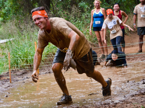 Dallas, USA - September 15, 2012: Dash of the Titans Mud Run Race. Unidentified male participant passes through a mud pit.