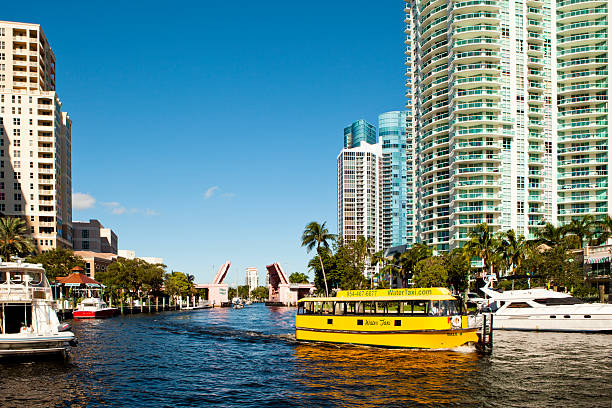 Water Taxi on the New River in Fort Lauderdale Fort Lauderdale, United States - September 8, 2012: A water taxi navigates on the New River in Fort Lauderdale in the morning. The New River runs through the downtown of Fort Lauderdale and connects to the many canals and the Intracoastal Waterway.  Water Taxis such as the one seen here are common and provide tours of the local landmarks and homes along the waterway. watertaxi stock pictures, royalty-free photos & images