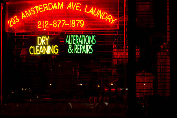 Interior of a retro style laundrette or laundromat with large steel washing machines and dryers, tables to fold cloths on and a retro tiled floor, evoking the 1960s and 1970s