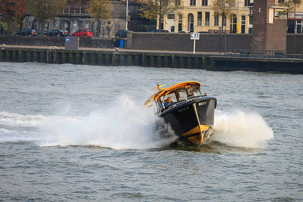 Water taxi on the New Meuse at Rotterdam Rotterdam, the Netherlands - October 29, 2011 : Man making a turn with a water taxi near the  Willemsbrug on the 'Nieuwe Maas' river ("New Meuse") towards the boompjeskade at Rotterdam, the Netherlands. watertaxi stock pictures, royalty-free photos & images