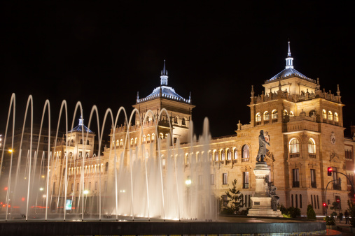 Valladolid, Spain - November 23, 2012: Plaza Zorrilla source and, at night, with the building of the Military Academy of Cavalry in the background, 1920