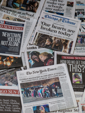 Carol Stream, IL, USA, December 22, 2012: Sandy Hook school shooting collage. A pile of local and national newspapers, many of them with headlines on the front pages reporting stories in the days immediately following the school shooting at sandy hook, Newtown CN.