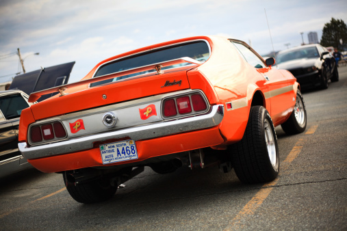 Woodside, Nova Scotia, A!anada - June 14, 2012: Low angle, rear view of a modified classic Ford Mustang in a parking lot near sunset on a cloudy evening. The iconic Ford Mustang is one of the most widely recognized production models to come from a domestic automobile manufacturer.