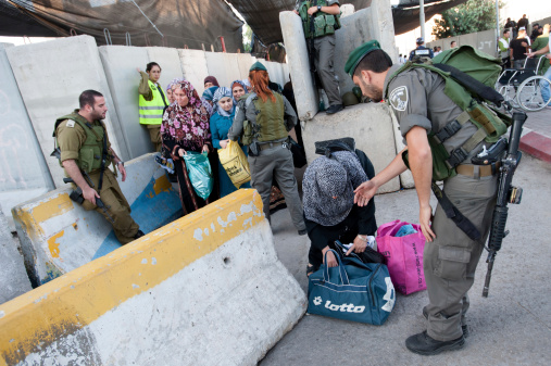 Bethlehem, Occupied Palestinian Territories - August 17, 2012: Israeli soldiers check Palestinian women and children at the Bethlehem checkpoint on the last Friday of Ramadan.