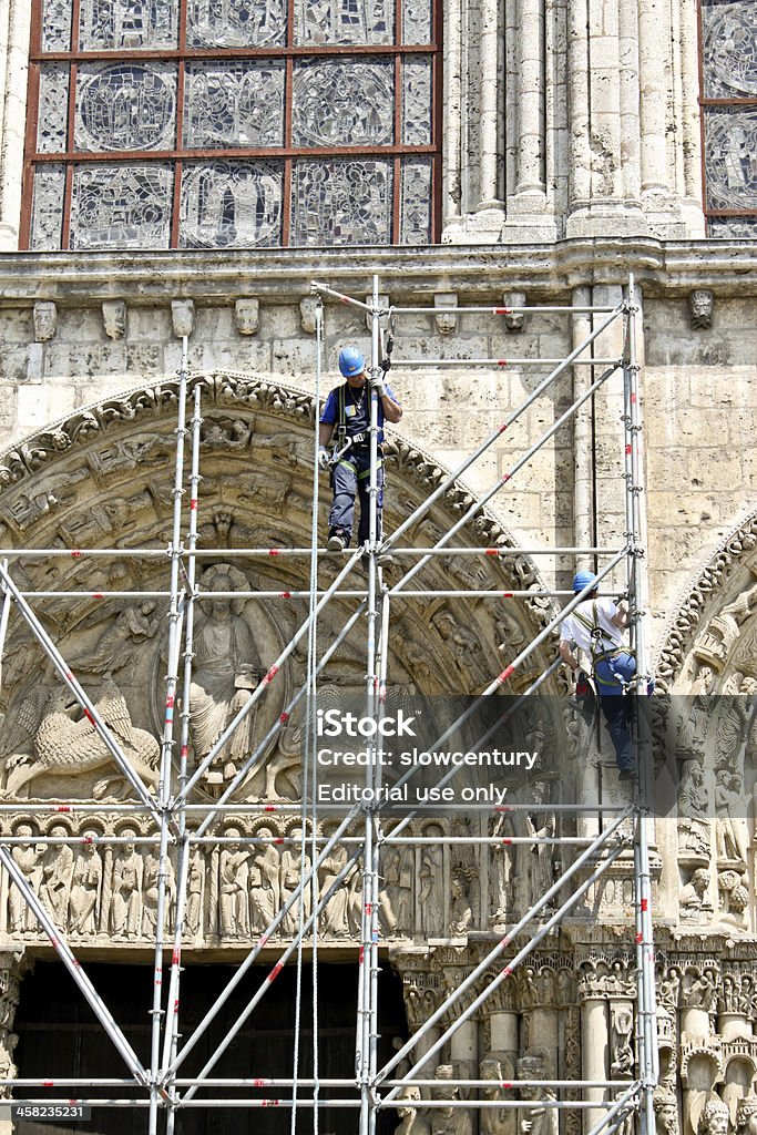 workers at reconstruction of Chartres cathedral Chartres, France - May 19, 2010: Workers restore exterior of the medieval Cathedral on May 19, 2010 in Chartres, France. The  cathedral is included in UNESCO world heritage list. Clambering Stock Photo