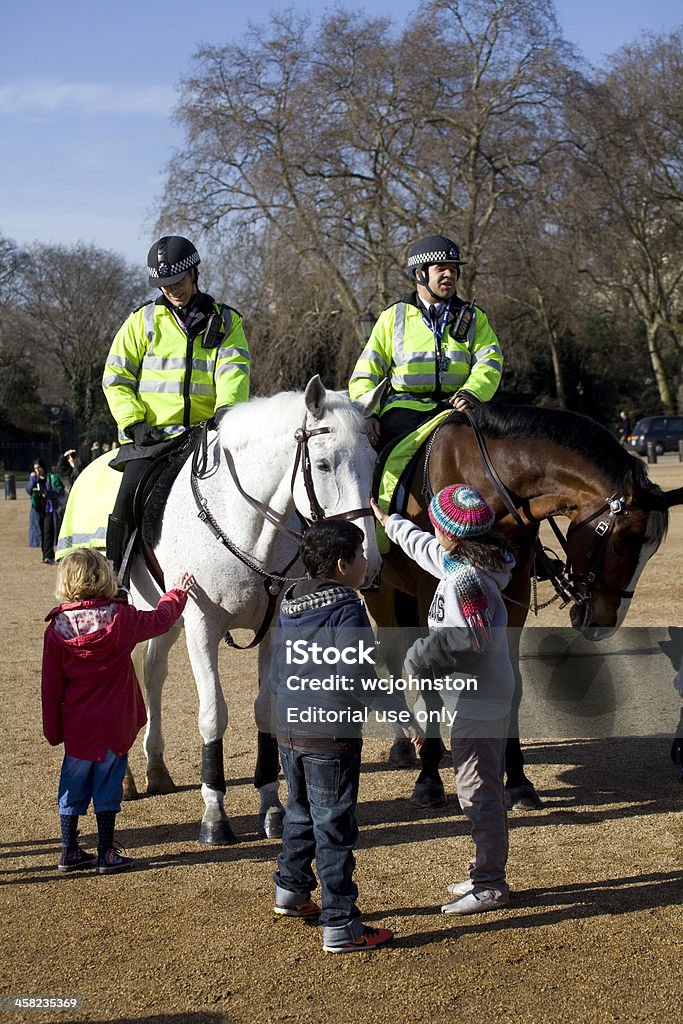 Niños pet dos caballos de policía montada - Foto de stock de Cuerpo de policía libre de derechos