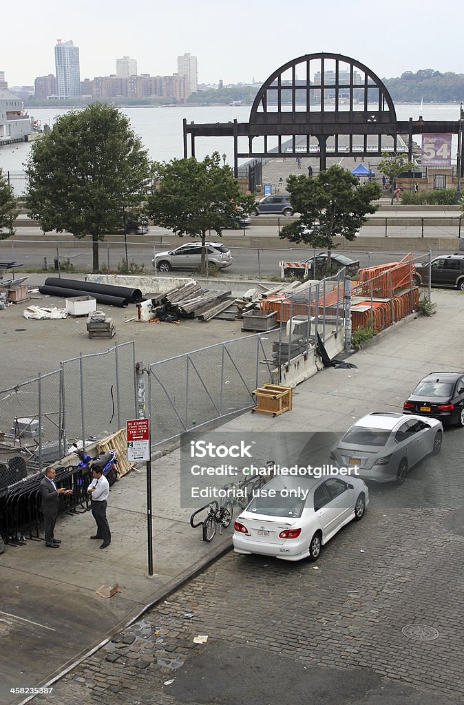 Men talking in New York's Meatpacking District New York, USA - August 25, 2012: Two men engaged in conversation in an industrial part of New York's Meatpacking District, with the Hudson River in the background. Adult Stock Photo