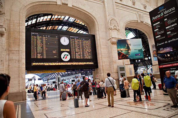 Central Milan Milan, Italy - July 20, 2012. The Milano Centrale train station is one of the largest train stations in Italy, and is designed using various architectural styles. People are idling as they watch the ticker for the latest information on the train they are hoping to catch. ticker tape machine stock pictures, royalty-free photos & images