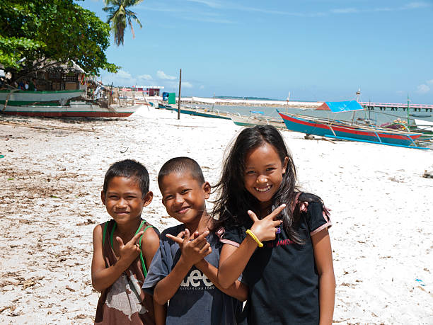 El Nido, Palawan, Philippines - April 3, 2012: Two boy and a girl smiling and making cute  gestures to camera at the beach.