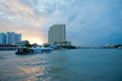 Bangkok, Thailand - July 2, 2012: view over the Chao Phraya River on sailing ferry and the skyline of modern Bangkok at sunset. The Chao Phraya River is the largest river in Thailand running through Bangkok to the Gulf of Thailand.