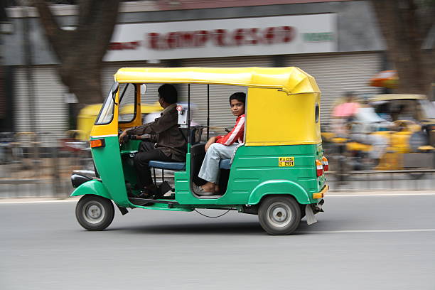 Auto rickshaw ride in Bangalore city Bangalore, India - August 8, 2010: Boy taking an Auto rickshaw ride in Bangalore city. auto rickshaw taxi india stock pictures, royalty-free photos & images